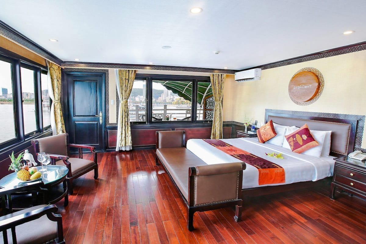 Une chambre d’hôtel avec un lit, un coin salon et une table avec des fruits.