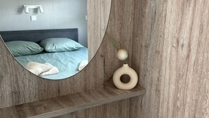 Een moderne slaapkamer met een houten wand, een ronde spiegel, een nachtkastje en een bed met groene beddengoed.