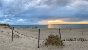 Een strand met een houten omheining en een redershut in de verte.