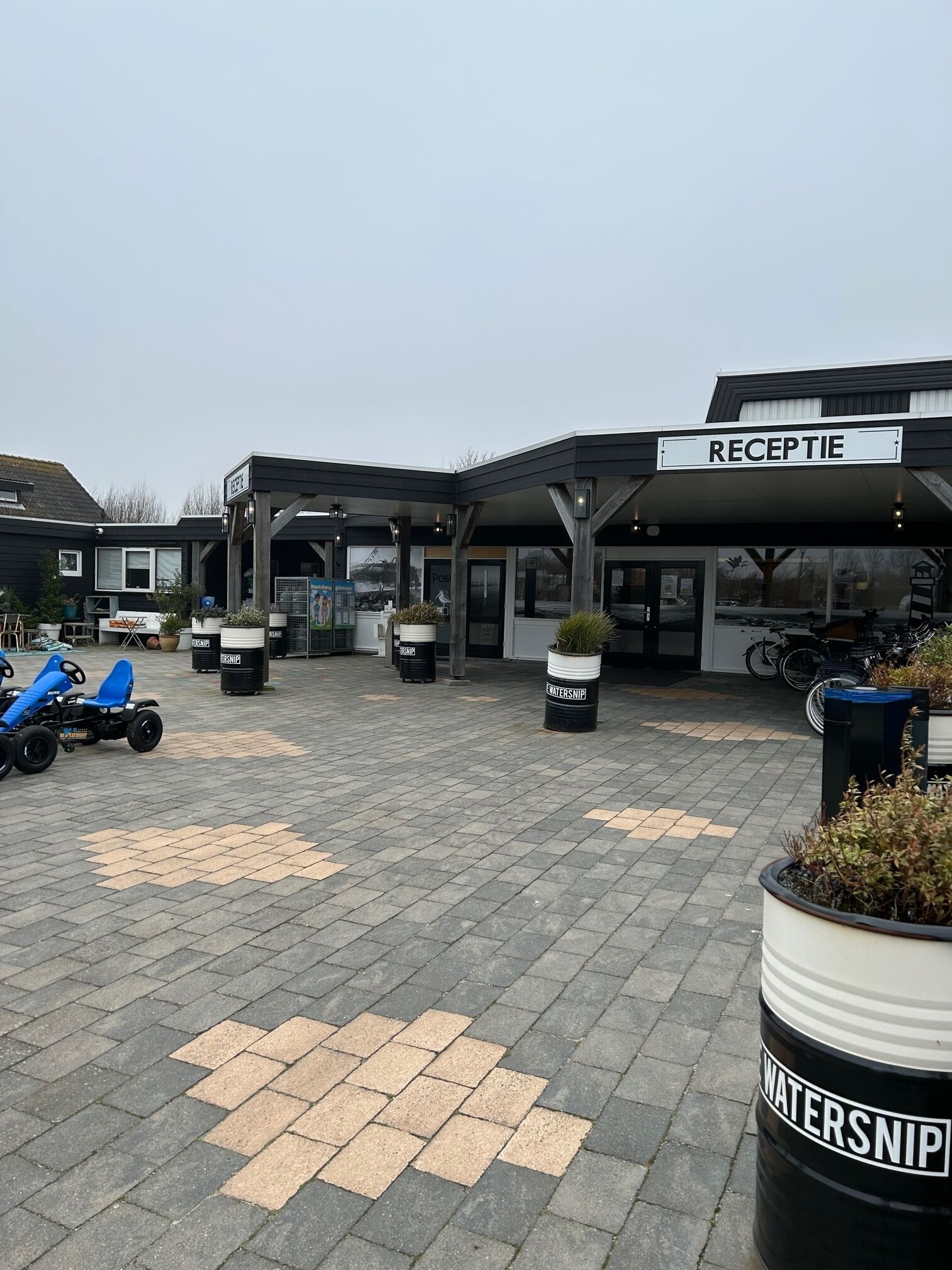A reception area with a sign, outdoor seating, and a blue go-kart.