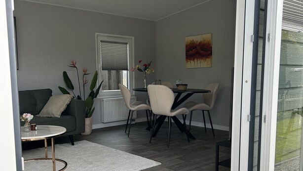 Een moderne woonkamer met een bank, salontafel en eethoek.