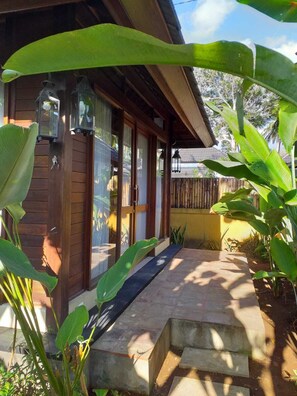Uma casa de madeira com varanda, portas de vidro e um caminho de concreto.