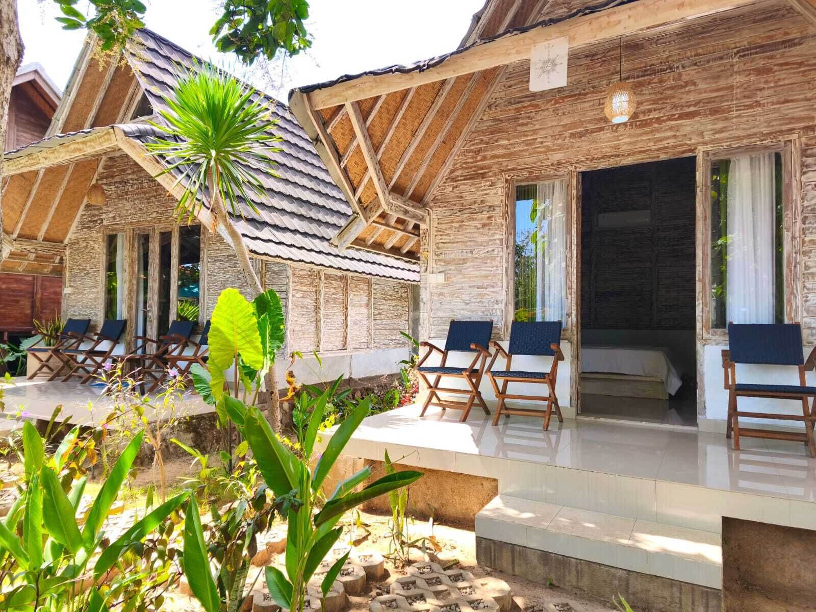 A wooden villa with a covered patio, outdoor seating, and a view of the surrounding landscape.