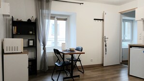 A compact kitchen with a dining table, chairs, a microwave, and a refrigerator.