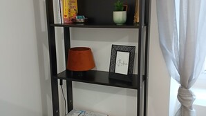 A black bookshelf with various items including books, a small potted plant, a framed picture, and a coffee maker.