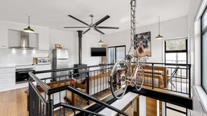 Open-plan living space with a high ceiling, central staircase, and a unique bicycle display.