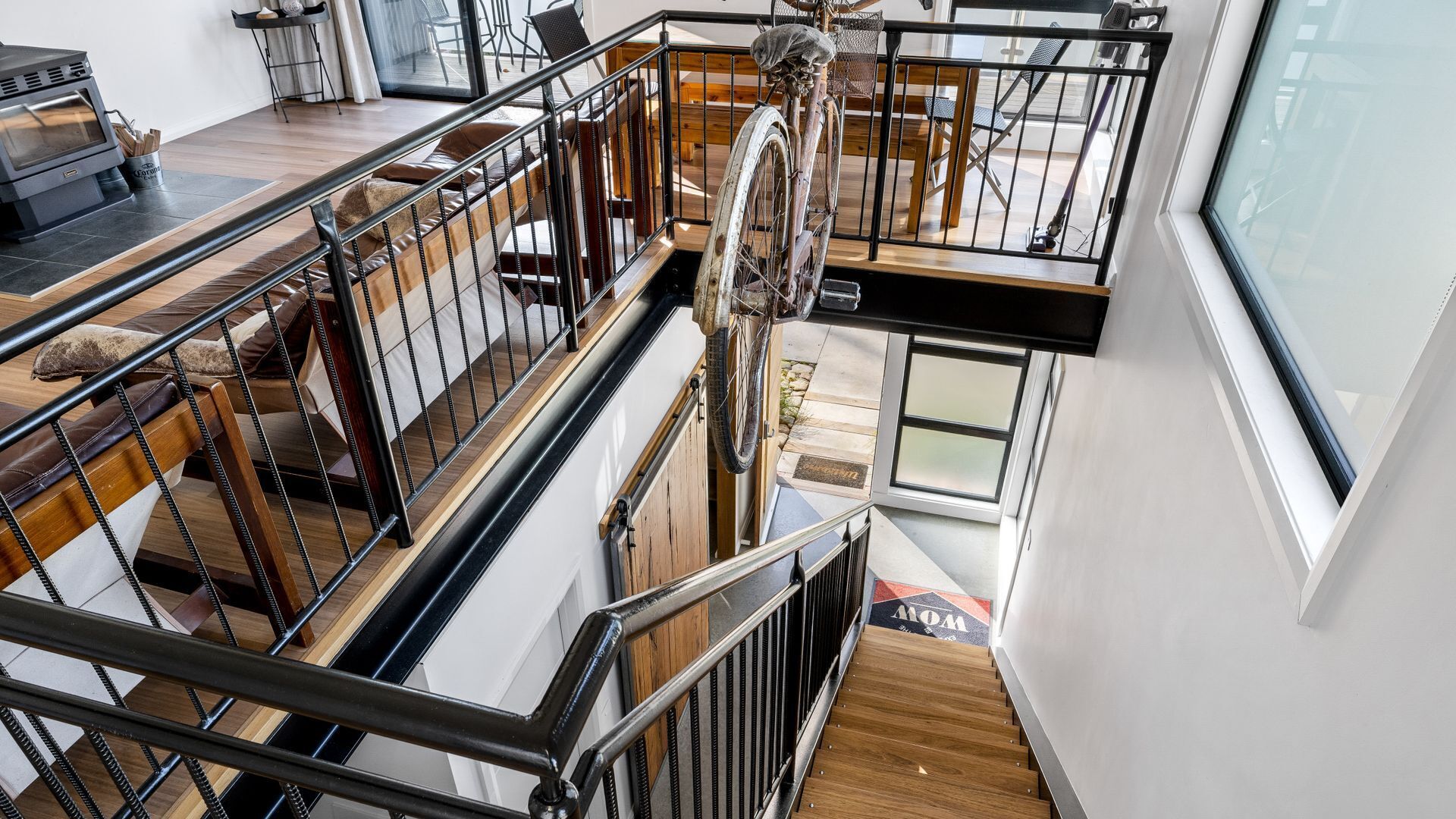 A multi-level interior with a staircase, wooden flooring, and a dining area with chairs and a table.