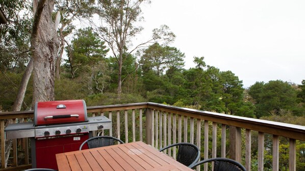 Un barbecue installé sur une terrasse extérieure, avec une table et des chaises en bois.
