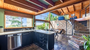 Enjoy a spacious kitchen with a sleek countertop, stainless steel appliances, and large windows offering a view of the surrounding greenery.