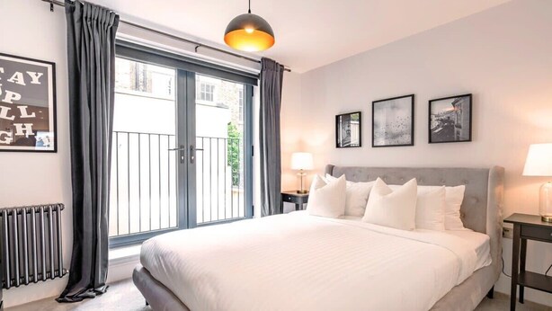 Ein Schlafzimmer mit einem großen Bett, Blick ins Freie und einem gerahmten Bild an der Wand.