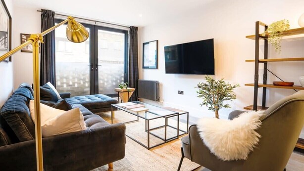 A modern living room with a sofa, armchair, coffee table, and a floor lamp.