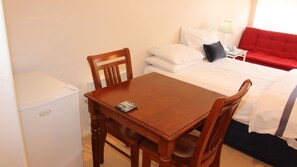 Cozy retreat with a single bed, dining table, and sofa, perfect for a relaxing stay.