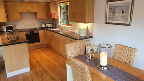 Una cocina moderna con armarios de madera, una mesa de comedor con sillas de mimbre y un centro de mesa con velas.