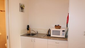 Een kleine keuken met een spoelbak, een magnetron en een klein aanrecht.