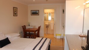 Une chambre d’hôtel comprenant un lit, un bureau avec une chaise, une salle de bain avec un lavabo et des toilettes, et un téléviseur posé sur un meuble.