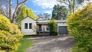 Une maison à deux étages avec un porche à l’avant, un garage et une allée menant à l’entrée.