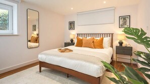 A bedroom with a bed, bedside tables, a mirror, and a window.