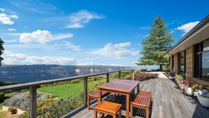 Een houten terras met een tafel en stoelen, met uitzicht op een schilderachtig canyonlandschap.