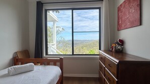 A bedroom with a large window, a bed, a dresser, and a view of the outdoors. - Emerald View @ Katoomba (Katoomba)