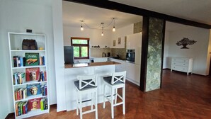 A modern kitchen with white cabinets, a wooden countertop, and a built-in oven. There is a window with a view of greenery outside.