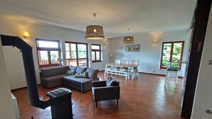 A spacious living area with a large sofa, a dining table, and a fireplace.