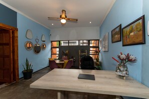 Una habitación con una mesa de madera, un ventilador de techo y una estantería.