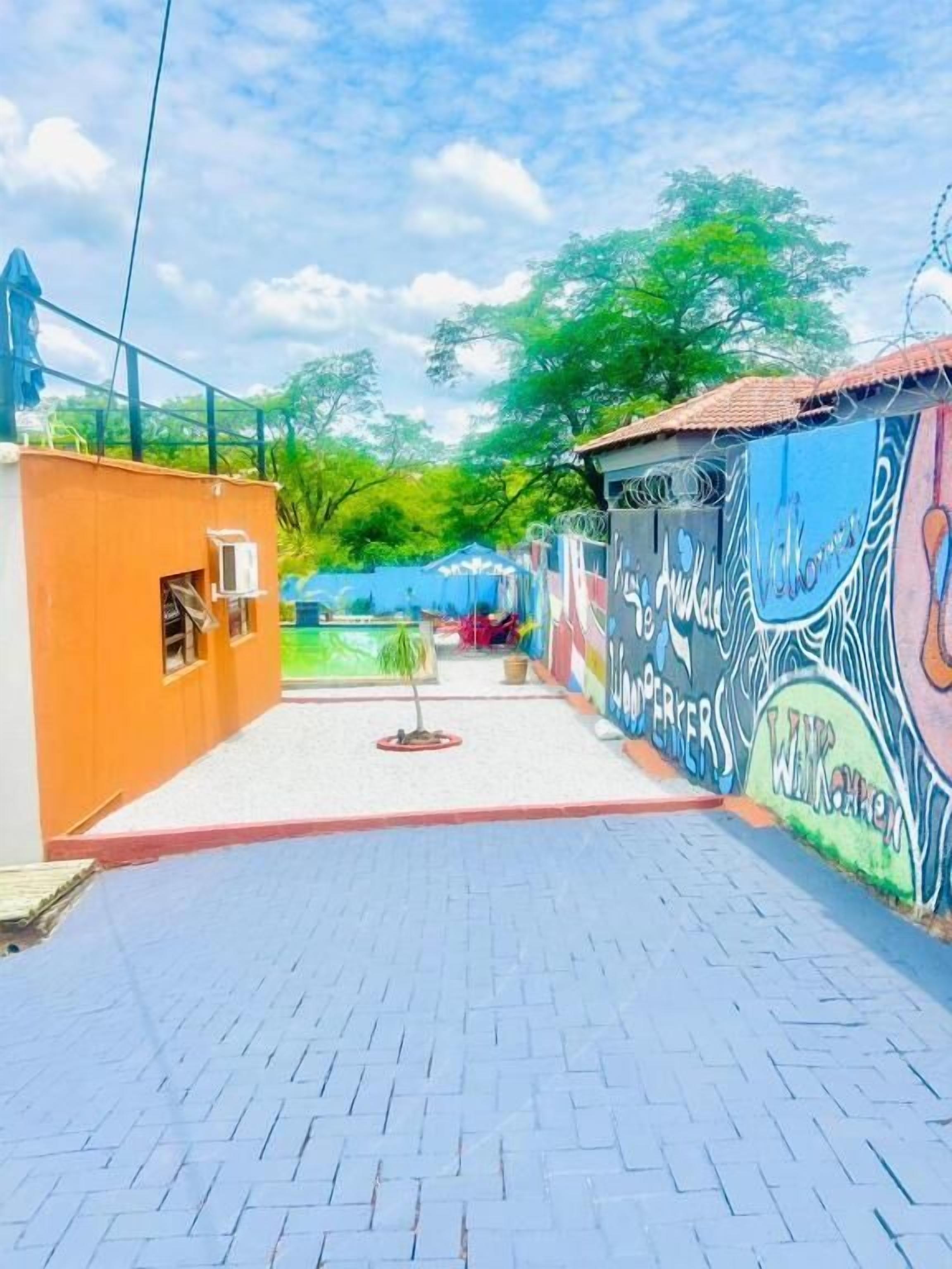 A paved pathway with a small tree and a building with colorful graffiti.