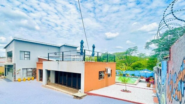 Un edificio moderno con techo plano, una estructura pequeña adosada y un patio empedrado.