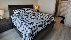 Ein Schlafzimmer mit einem Bett, einem Nachttisch, einer Lampe, einem Deckenventilator und einer Tür mit einem Streifenvorhang.
