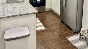 A kitchen with white cabinets, stainless steel appliances, a granite countertop, and a wooden floor. - Relax Near Beach, Shops, Parks, Mayo Clinic, Quick Drive to Downtown & Stadium (Jacksonville Beach)