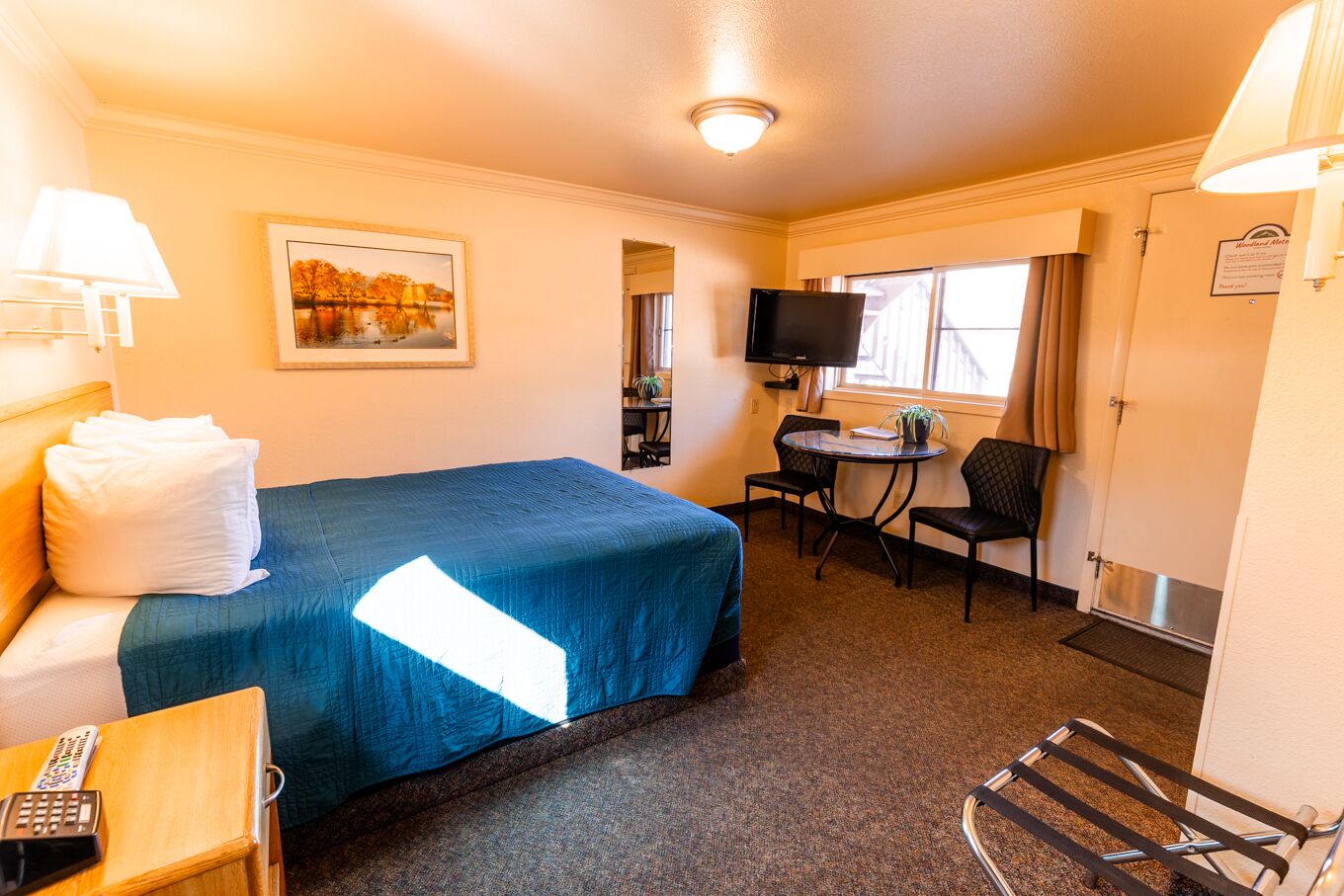 A hotel room with a bed, a desk, a chair, a TV, and a window.