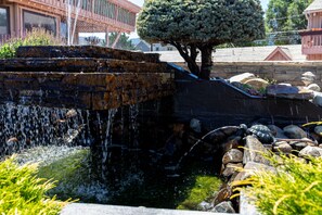 A waterfall feature with a stone structure, a tree, and surrounding rocks.