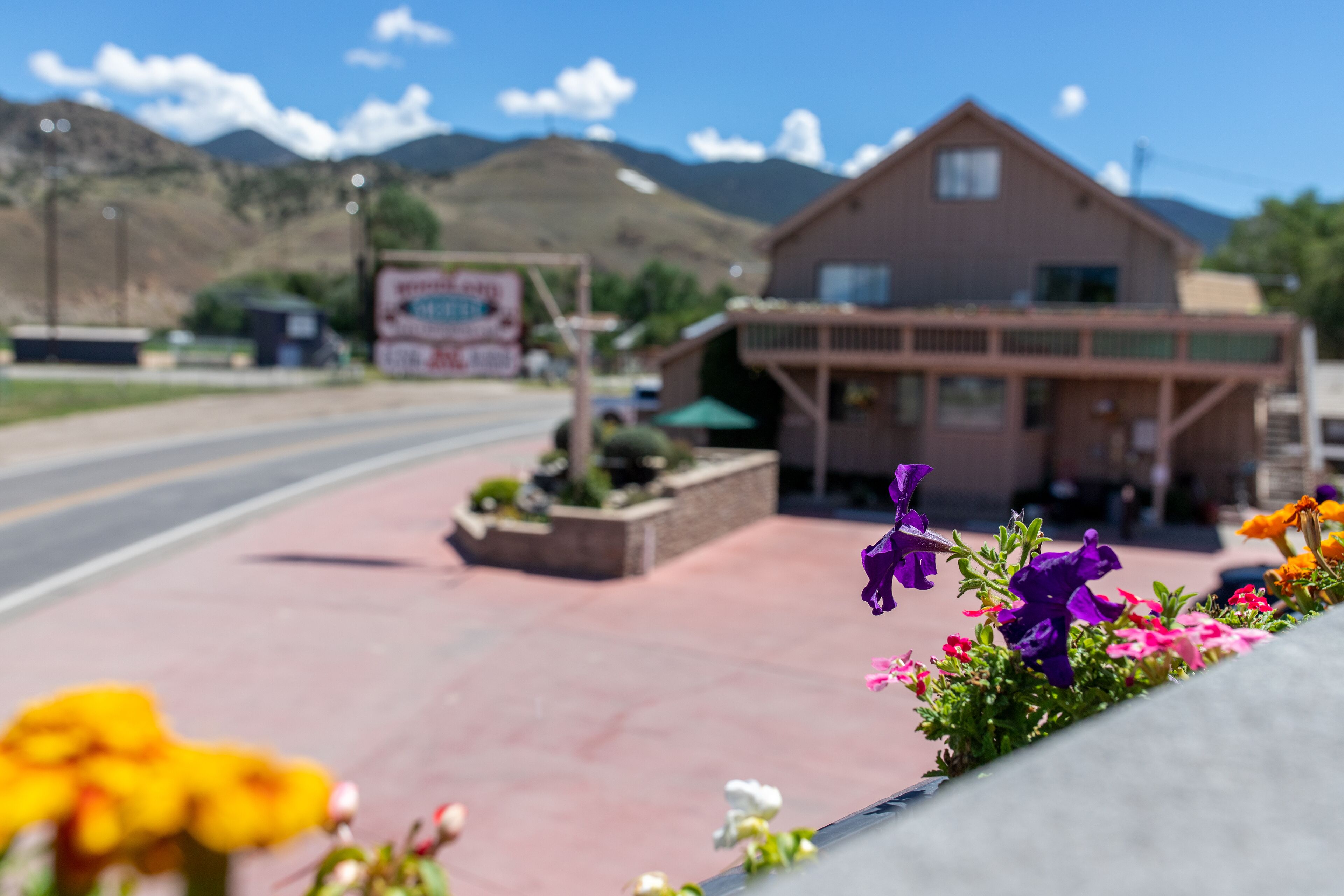 A building with a porch and flower beds in front.