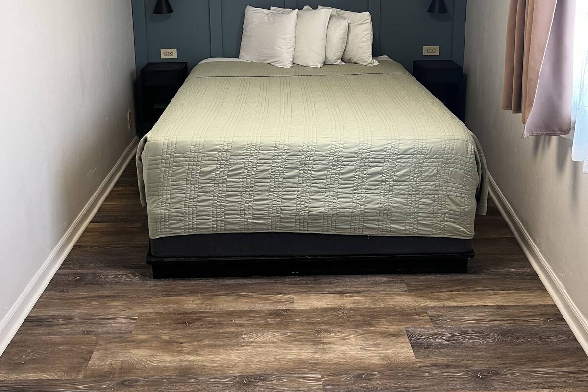 A bedroom with a bed, a ceiling fan, and a nightstand.