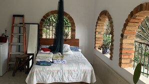 Une chambre à coucher avec un lit, une échelle, une chaise et une grande fenêtre donnant sur un paysage verdoyant.