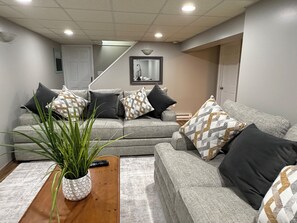 A modern living room with a grey sofa set, a wooden coffee table, and a potted plant. - Boho Chic Cape (Albany)