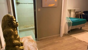 Een kamer met een houten vloer, een wereldkaart aan de muur, een bed met een groene deken en een gorilla-beeldje.