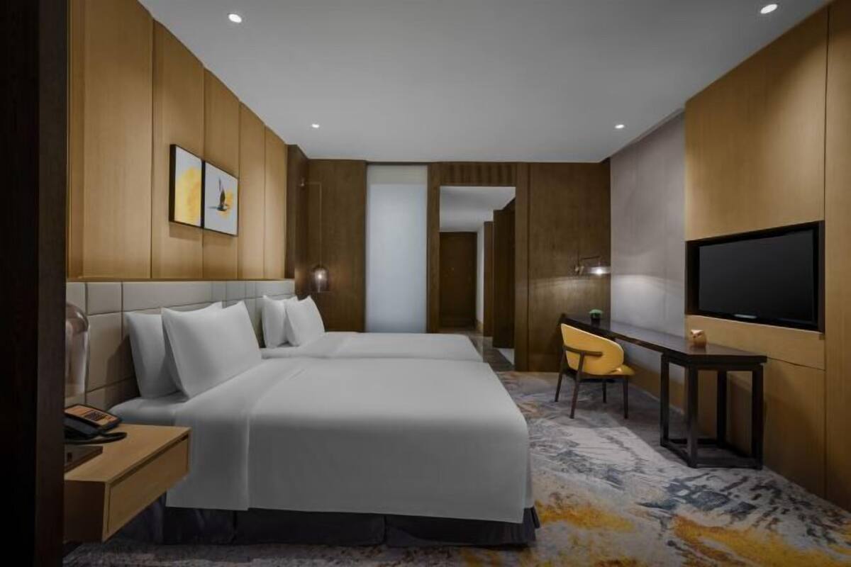 Een moderne hotelkamer met een groot bed, een bureau, een stoel, een televisie en kunst aan de muur.