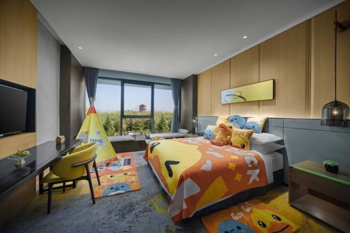 Een moderne hotelkamer met een groot bed, een bureau, een stoel en uitzicht op het omliggende landschap.