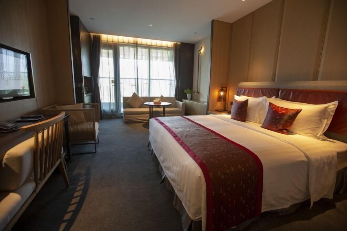 Ein Hotelzimmer mit einem großen Bett, einem Schreibtisch, einem Sessel und einem kleinen Tisch.