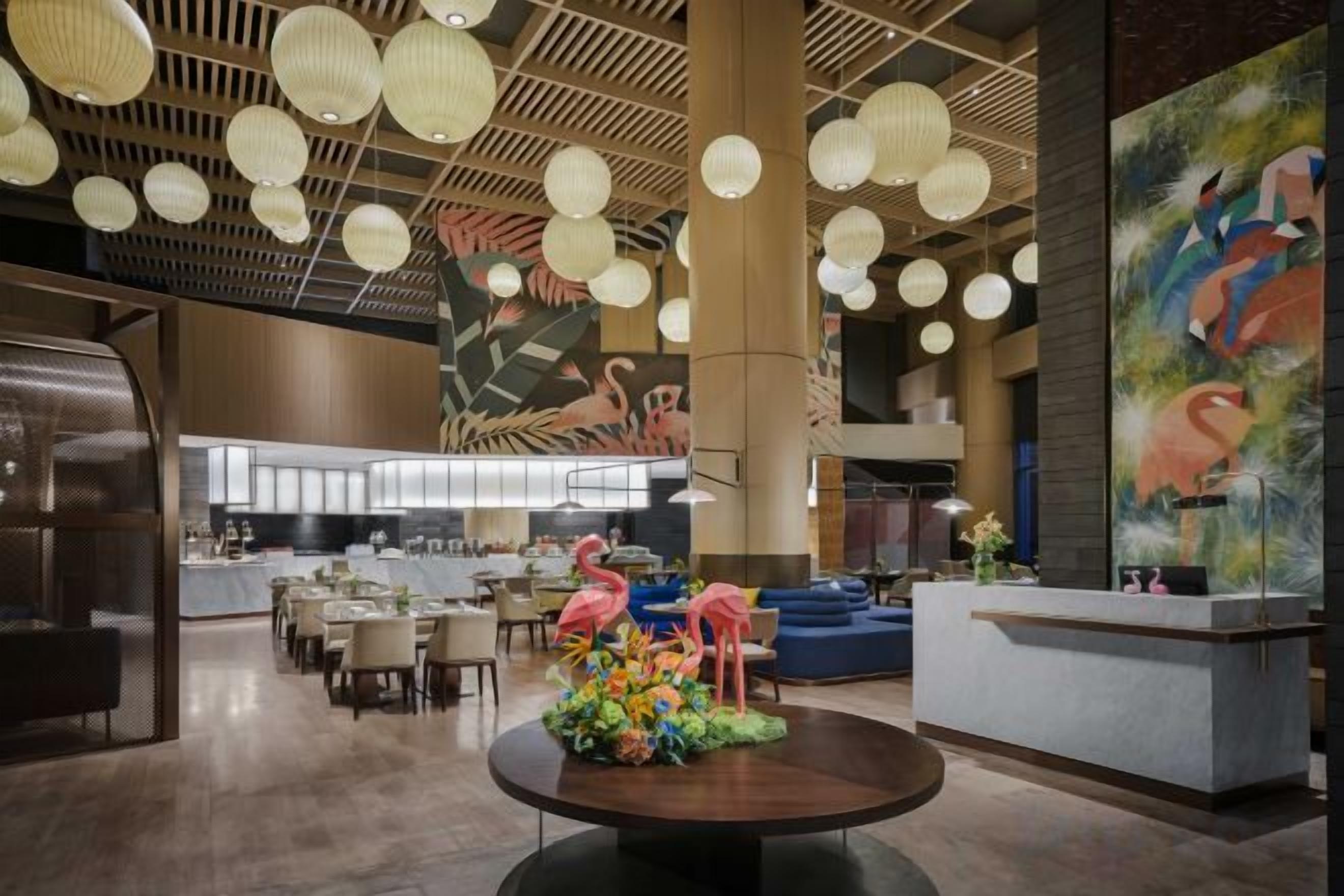 A spacious lobby with a central round table, seating area, and a reception desk.