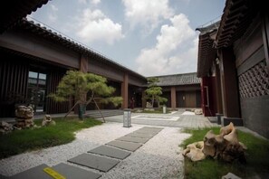 Ein traditioneller japanischer Innenhof mit Steinwegen, Holzbauten und Steinbildhauereien.