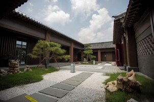A traditional Japanese courtyard with stone pathways, wooden buildings, and stone sculptures.