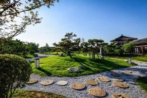 Um jardim japonês tradicional com um caminho, lanternas de pedra e uma pagoda.