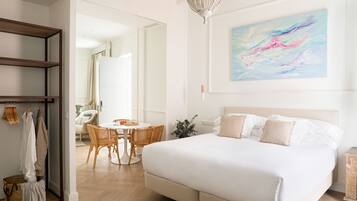 A modern bedroom with a large bed, a dining area, and a hallway leading to another room.