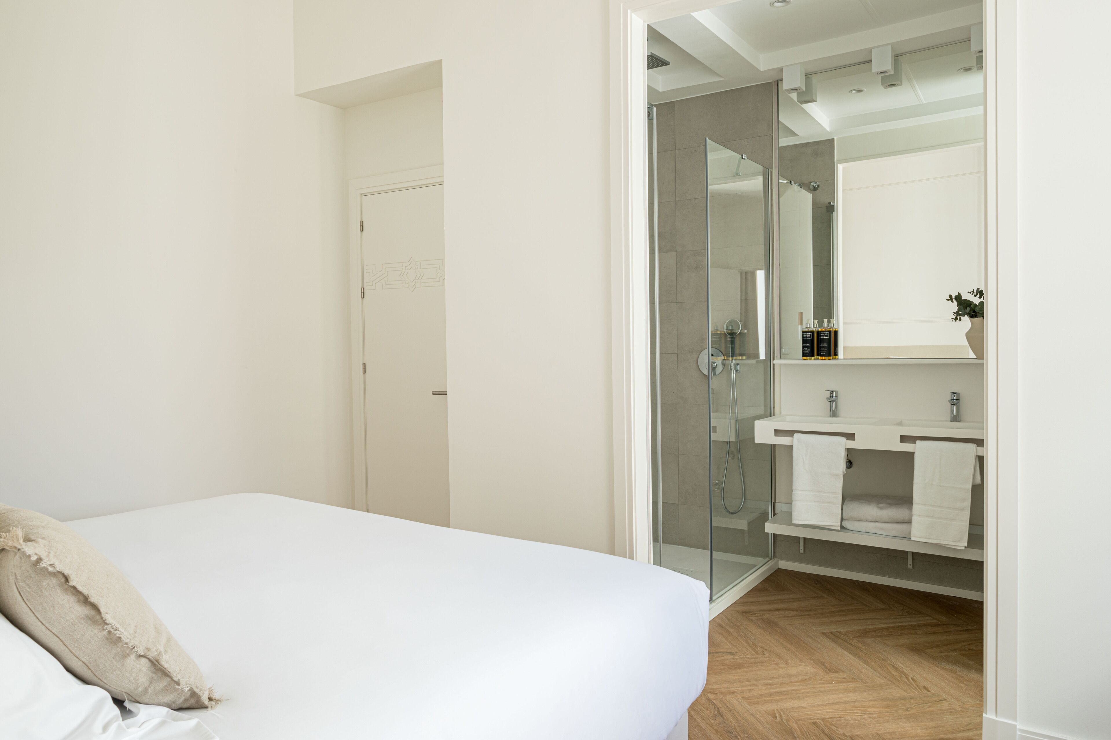 Ein Schlafzimmer mit einem Bett, ein Badezimmer mit einer Duschkabine aus Glas und einem weißen Waschbecken.