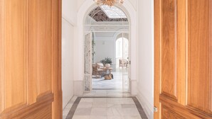 A hallway with wooden doors, a chandelier, and a view into a room with a round table and chairs. - MYLU SUITES by PUERTA CATEDRAL (Seville)