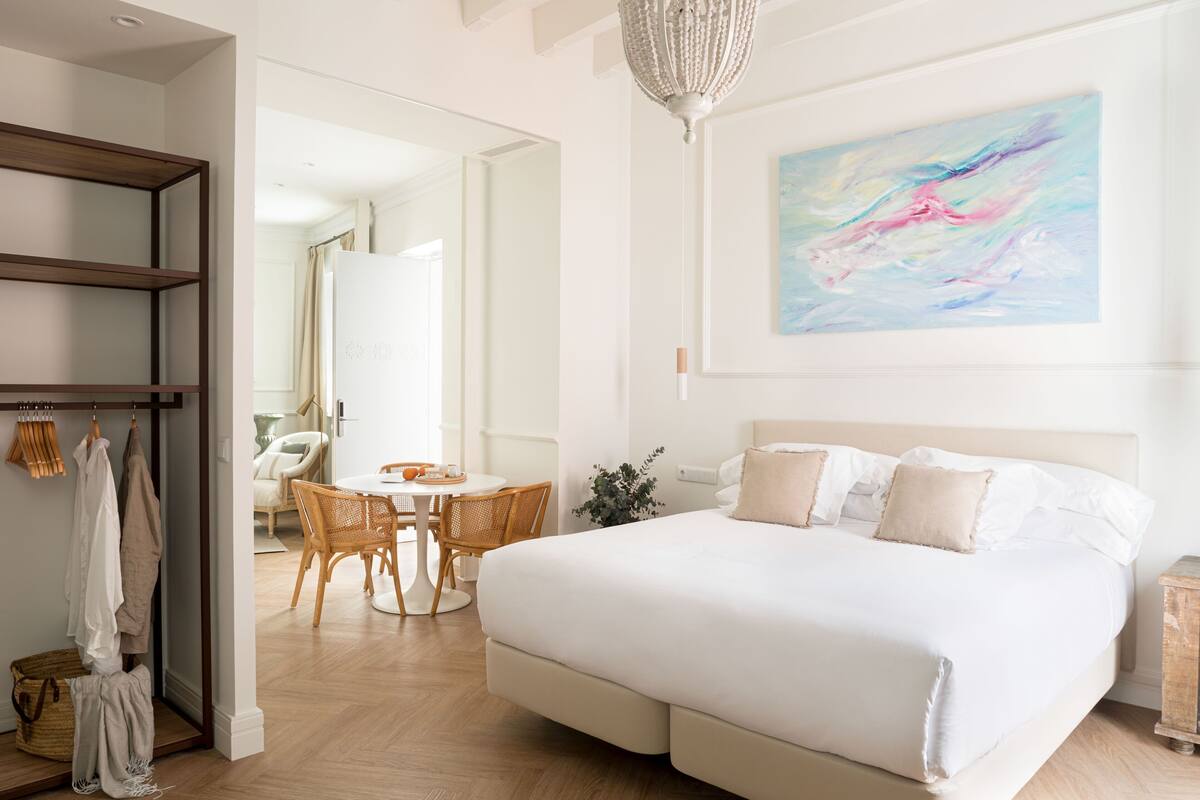 A bedroom with a large bed, a dining area, and a wardrobe.