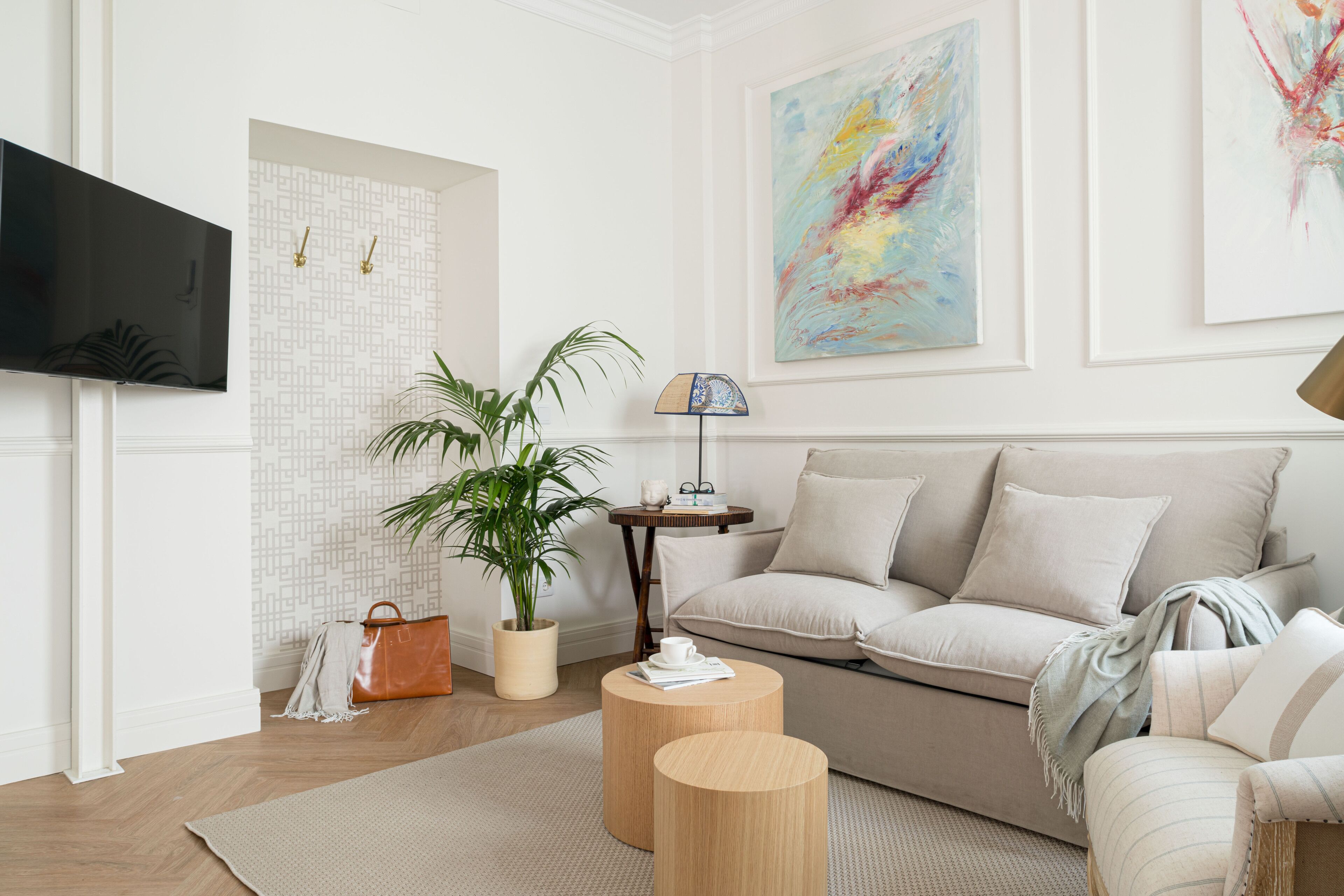 Una sala de estar moderna con un sofá, una mesa de centro, un televisor, una planta y obras de arte en las paredes.