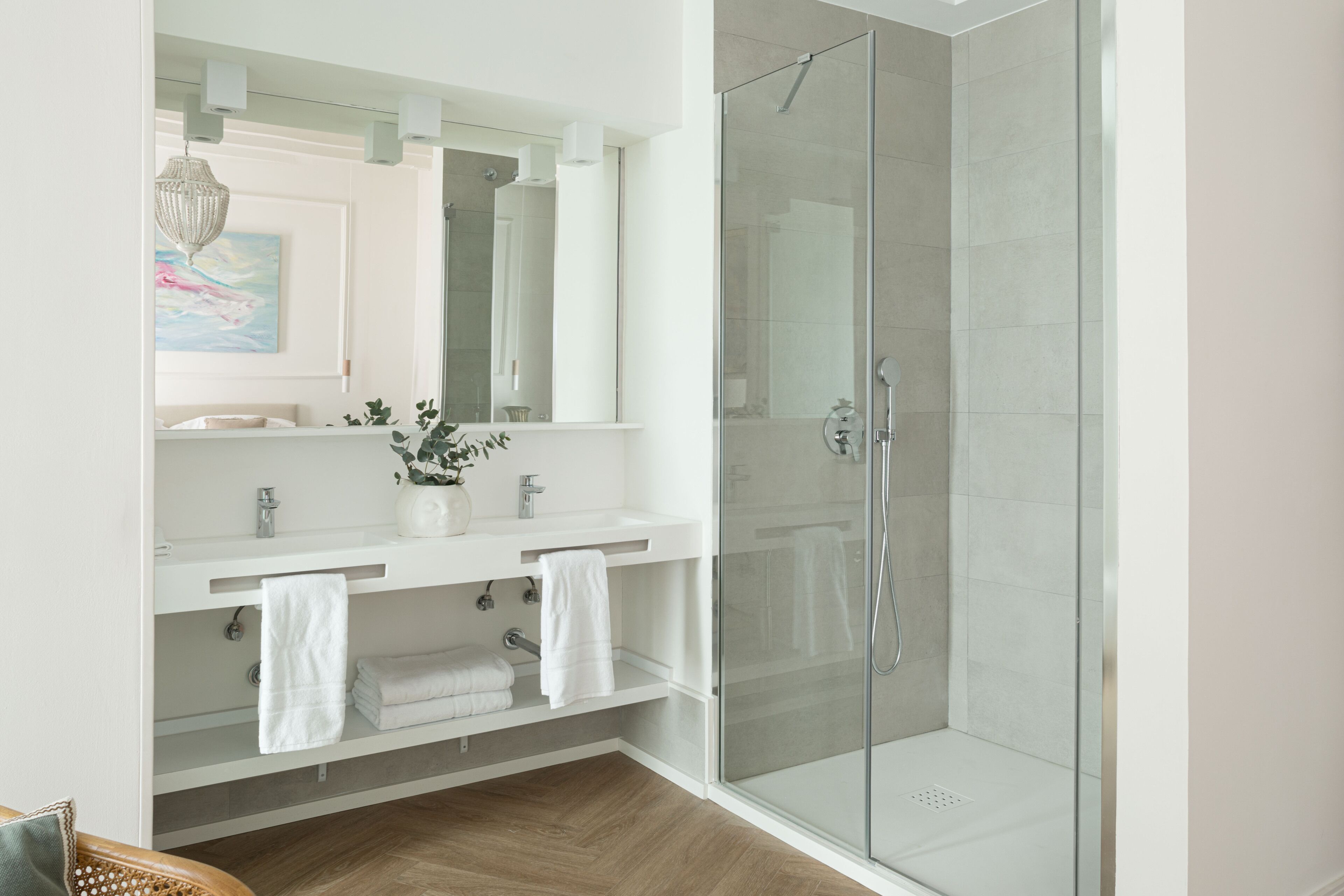 A modern bathroom with a glass shower enclosure, a white vanity with two sinks, and a large mirror.